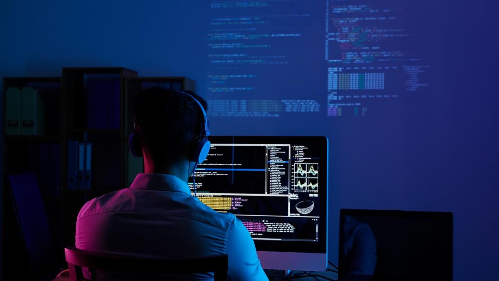 Entwickler bei der Arbeit am Code spät in der Nacht, Blick von hinten