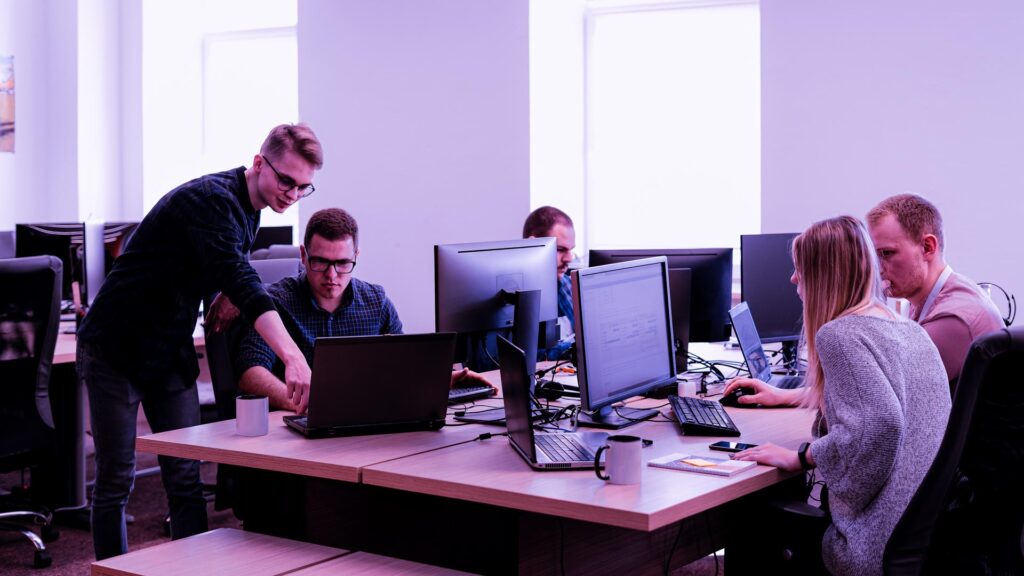 Full concentration at work. Group of young business people working and communicating while sitting at the office desk together with colleagues sitting in the background