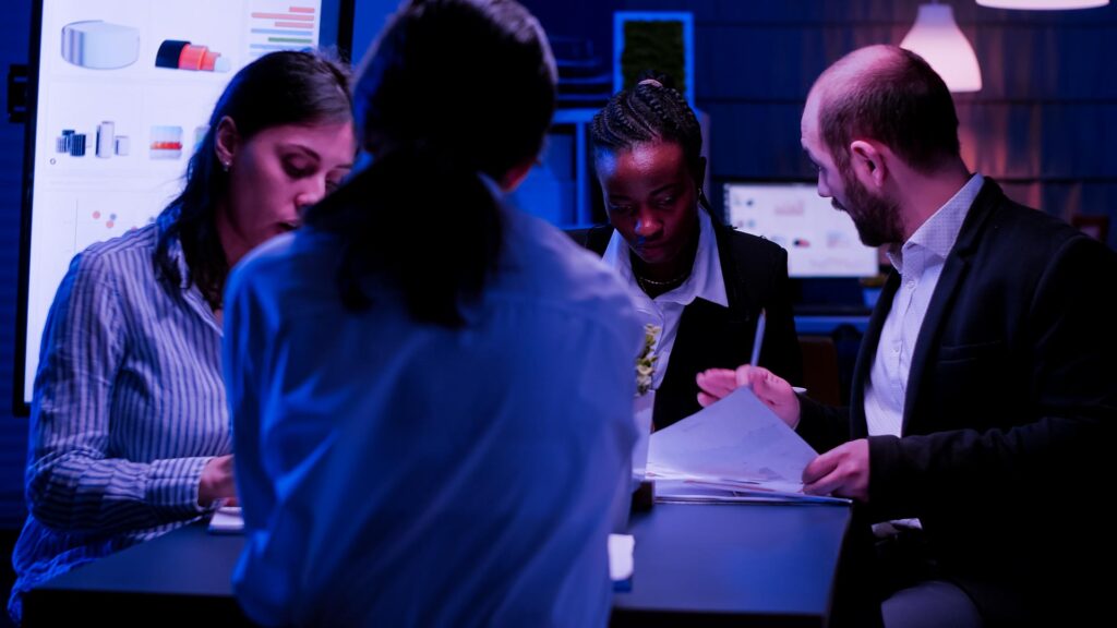 Diverse Unternehmen Unternehmer sitzen am Konferenztisch arbeiten an Management-Lösung Präsentation im Büro Tagungsraum spät in der Nacht. Multiethnische Teamarbeit beim Brainstorming von Ideen.