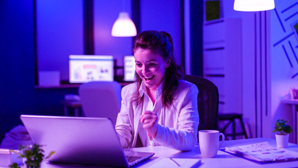 Arbeit mit Diagrammen. Mann arbeitet im Büro allein während COVID-19 Quarantäne, bleiben bis spät in die Nacht. Junger Geschäftsmann, Manager erledigt Aufgaben mit Smartphone, Laptop, Tablet in leeren Arbeitsbereich.